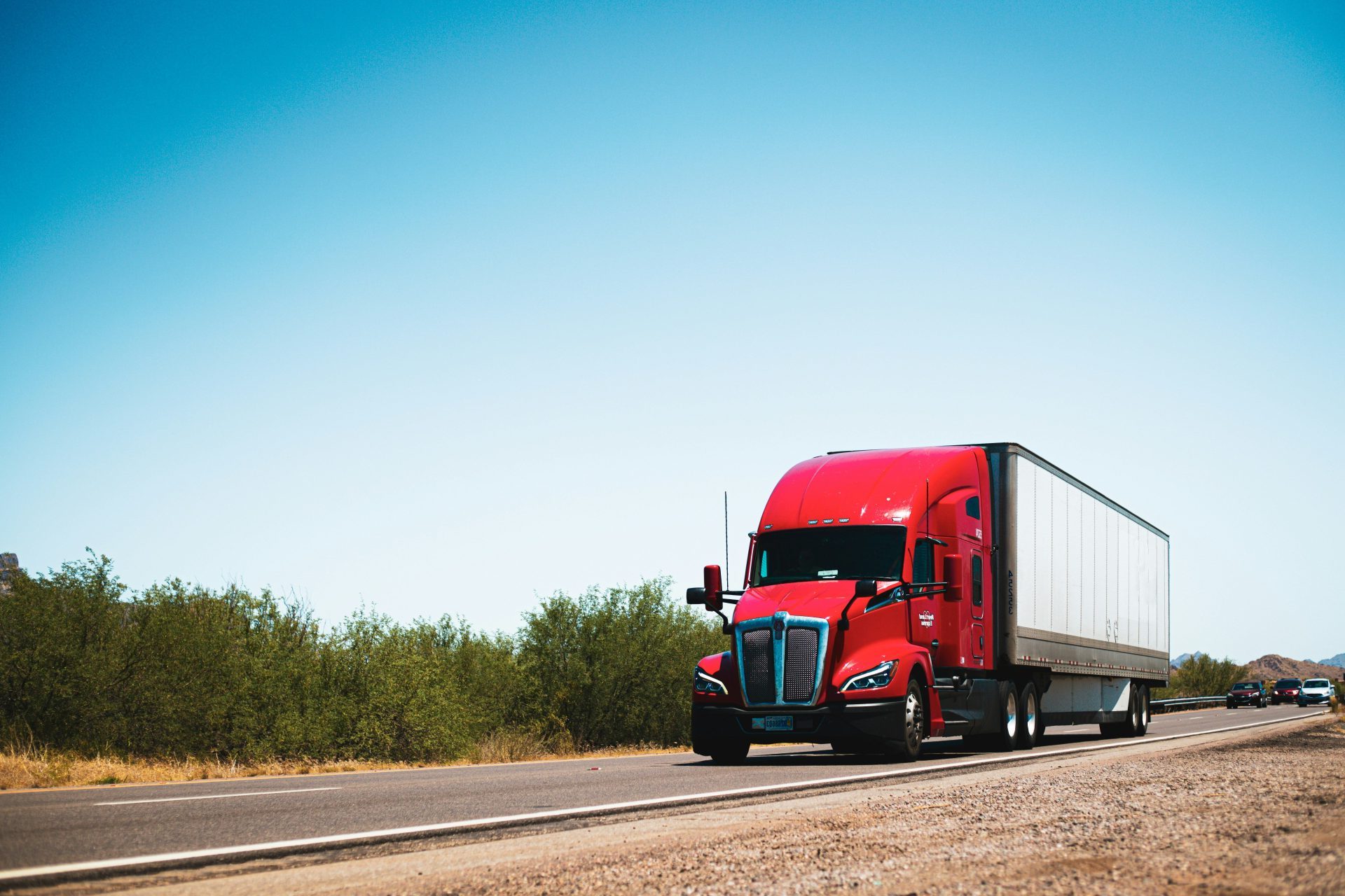A red semi truck driving down a country road